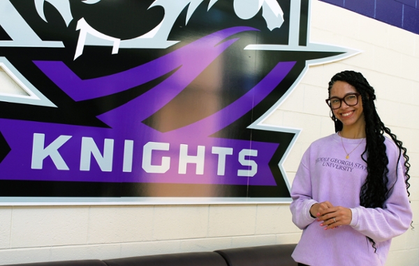 Yanelis Rodriguez by the MGA Knights athletics logo in the Volleyball Gym. 